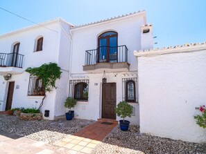 A white building with a brown door, potted plants, and a tiled entrance. - Capistrano Village Casa Corasol by Interhome (Nerja)