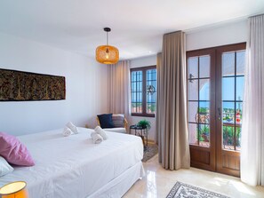 Une chambre d’hôtel avec un grand lit, une chaise, une petite table avec une plante et une vue sur l’extérieur par une fenêtre.