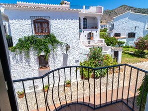 Un bâtiment blanc doté d’un balcon, de plantes en pot et d’un panneau indiquant un espace jardin.