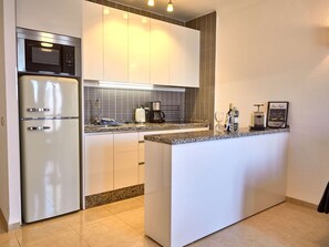Eine moderne Küche mit integriertem Kühlschrank, einer Kaffeemaschine und einer kleinen Kochinsel mit Spüle.