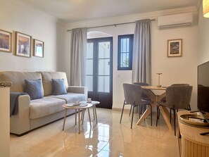 A modern living room with a sofa, a dining table with chairs, and a TV. - Casa Sofia Capistrano Village Pueblo 110B by Interhome (Nerja)