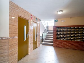Ein Flur mit Treppe, einer Tür mit Rauchverbot-Hinweis und einer Wand mit Briefkästen.