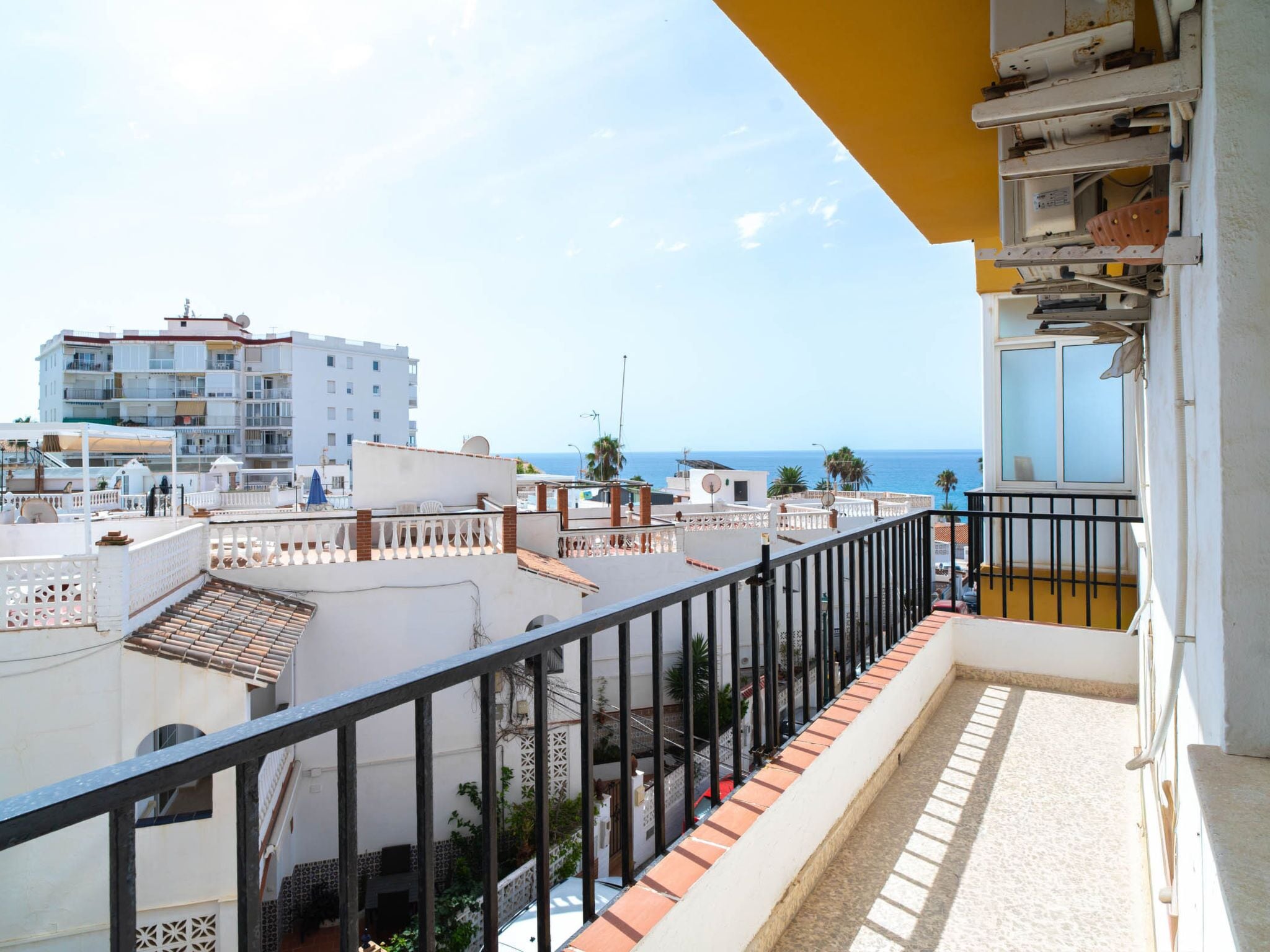 Ein Balkon mit Blick auf das Meer und angrenzende Gebäude.
