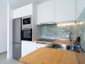 A modern kitchen with stainless steel appliances, a wooden countertop, and a tiled backsplash. - Capistrano Village Deluxe Garden by Interhome (Nerja)