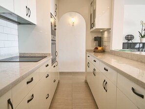 A kitchen with white cabinets, a marble countertop, and a tiled backsplash. - Casablanca 9 Punta Lara by Casasol by Interhome (Nerja)