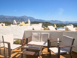 Eine Terrasse mit Korbmöbeln und Blick auf Berge.