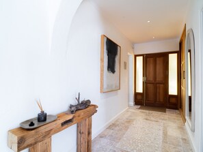 A hallway with a wooden console table, a painting, and a wooden door. - Villa La Casita Fuente del Baden 52 by Casasol by Interhome (Nerja)
