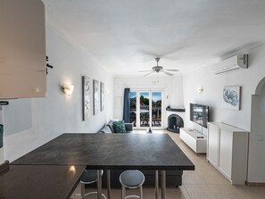 Eine moderne Küche mit Kochinsel, Barhocker, Essbereich mit Sofa und Kamin.