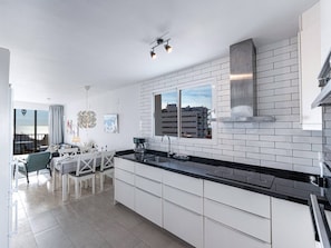 A modern kitchen with white cabinetry, a black countertop, and a window overlooking a cityscape. - Miami 5 Seaview by Casasol by Interhome (Nerja)