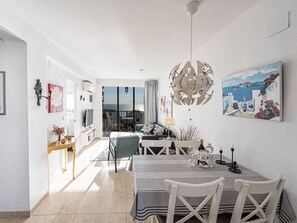 Ein modernes Wohnzimmer mit Essbereich und Aussicht, versehen mit einer großen, dekorativen Leuchte.