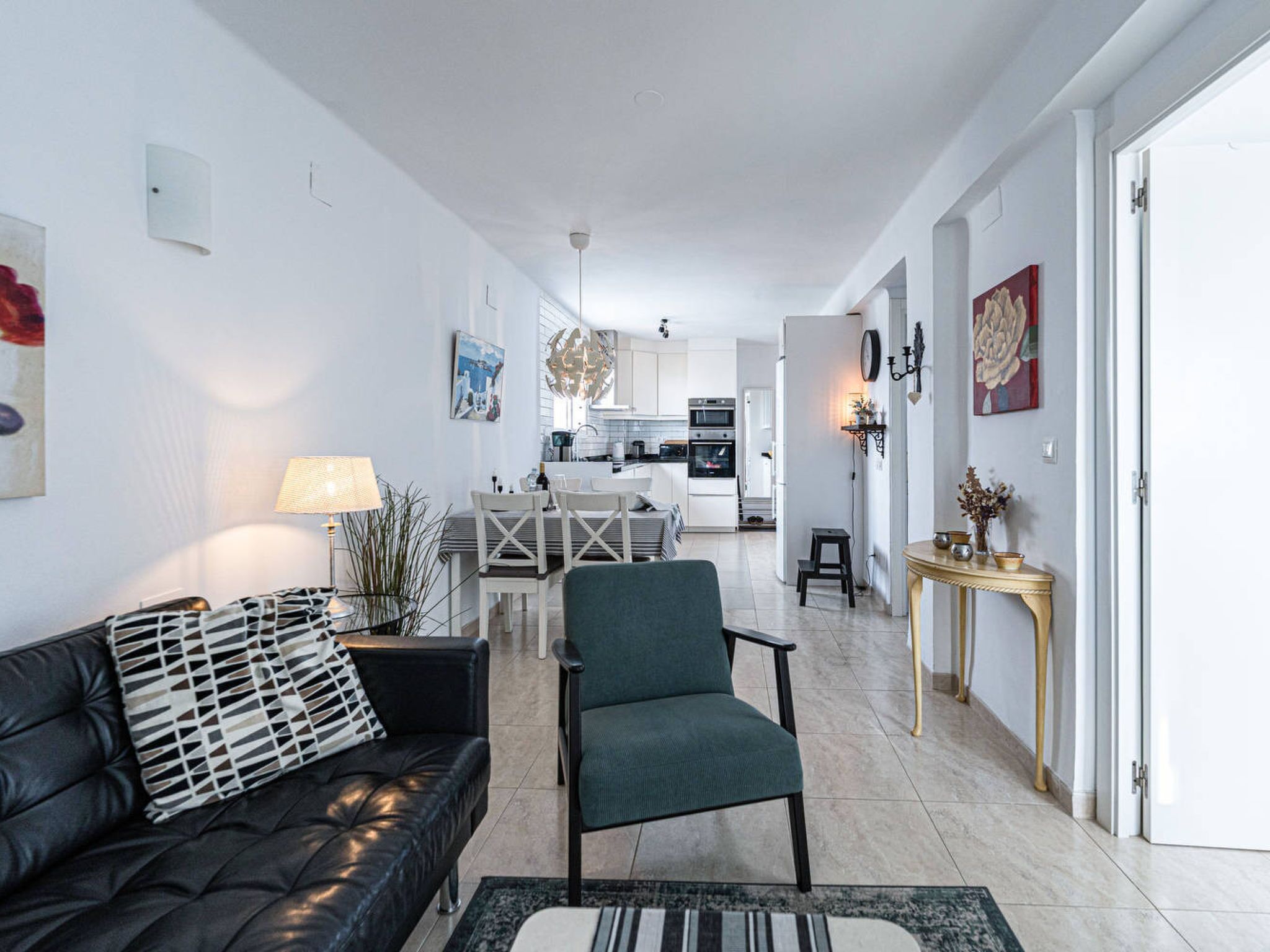 Een moderne woonkamer met een zwarte leren bank, een groene fauteuil en een kamerkleed met een patroon.