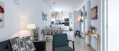 Een moderne woonkamer met een zwarte leren bank, een groene fauteuil en een kamerkleed met een patroon.