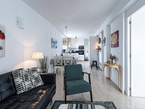 Un salon moderne avec un canapé en cuir noir, un fauteuil vert et un tapis à motifs.