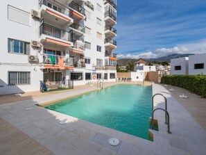Un immeuble résidentiel doté d’une piscine, de balcons et offrant une vue dégagée sur le paysage environnant.