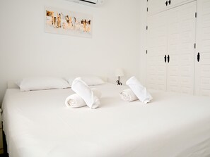 Ein Hotelzimmer mit einem Bett, zwei aufgerollten Handtüchern, einem Bild an der Wand und einem Kleiderschrank.
