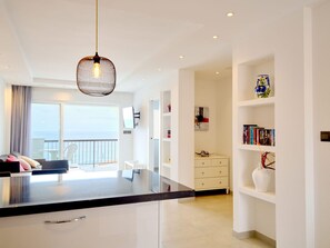 Een moderne keuken met een centraal eiland, witte kastjes en een hangende lamp.