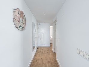 A hallway with wooden flooring, white walls, and a door leading to a bedroom. - Luxury Pool View Isea 1111 by Interhome (Torrox Costa)