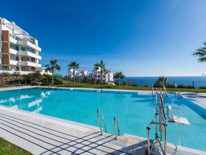 A clear blue swimming pool with a view of the ocean and a modern building in the background. - Luxury Pool View Isea 1111 by Interhome (Torrox Costa)