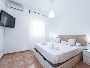A hotel room with a bed, a TV mounted on the wall, and a window with curtains. - Torrecilla Urban Beach Stay by Interhome (Nerja)