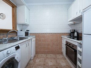 A compact kitchen with a washing machine, microwave, and a coffee maker. - Apartment  by Interhome (Nerja)