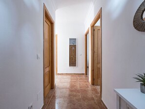 A hallway with wooden doors, a tiled floor, and a wall-mounted light fixture. - Apartment  by Interhome (Nerja)