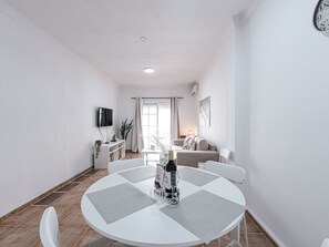 A modern living room with a dining area, a flat-screen TV mounted on the wall, and a large window with curtains. - Apartment  by Interhome (Nerja)