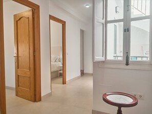 A hallway with a wooden door, a bed, and a window with a view. - Casa Chica Calle Cristo 112 by Casasol by Interhome (Nerja)