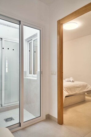 Hotellihuone, jossa on sänky, puuovi ja näkymä lasiovesta.