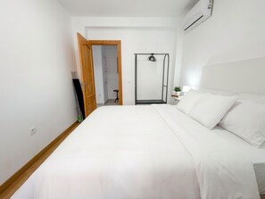 A bedroom with a bed, a wardrobe, a mirror, a small table with a lamp, and an air conditioning unit. - Casa Chica Calle Cristo 112 by Casasol by Interhome (Nerja)