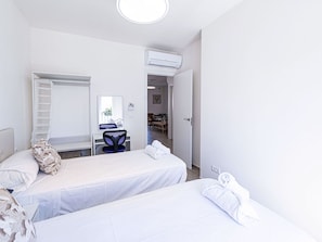 A hotel room with two beds, a desk, a chair, and an air conditioning unit. - Hacienda 4A by Casasol by Interhome (Nerja)