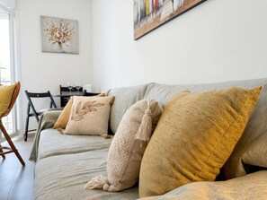 Ein Wohnzimmer mit einer Couch, zwei Sesseln, einem Tisch mit Gläsern und einem Bild an der Wand.