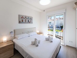 Ein Hotelzimmer mit einem großen Bett, einem Bild an der Wand und einem Balkon mit Blick.