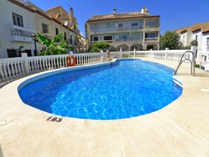 A swimming pool with a white balustrade, a lifebuoy, and a building with balconies in the background. - Hacienda 4A by Casasol by Interhome (Nerja)