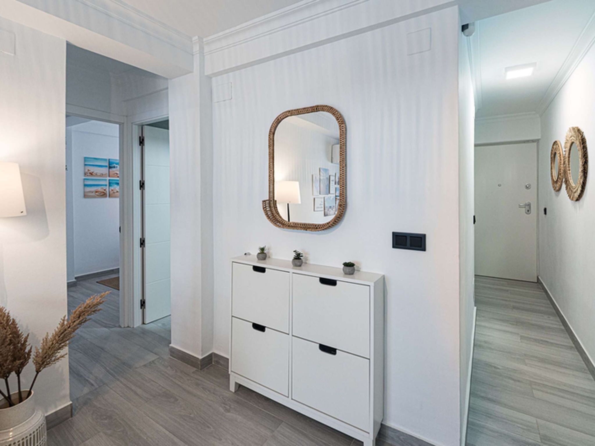 A hallway with a white console table, a mirror, and a door leading to another room.