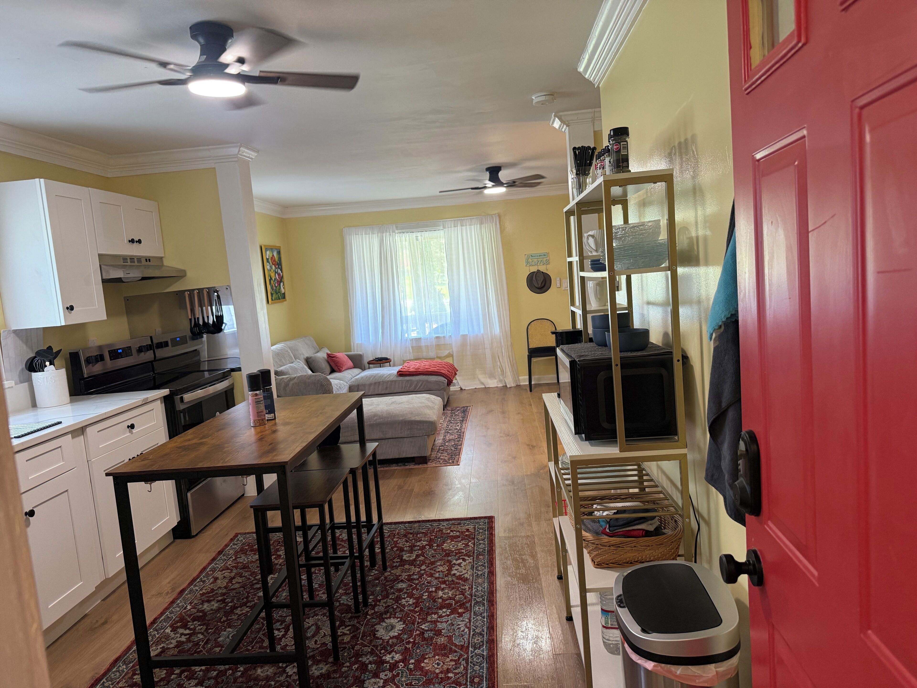 Una cocina compacta con comedor, una puerta roja y un ventilador de techo.