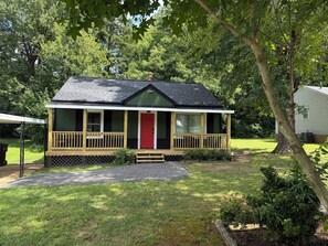 A single-story house with a porch, a red door, and a small front yard. - Lovely house in High Point perfect for your next getaway, located next to HPU! (High Point)
