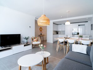 A modern living room with a flat-screen TV, a sofa, a coffee table, and a dining area with a table and chairs. - Apartment  by Interhome (Torrox Costa)