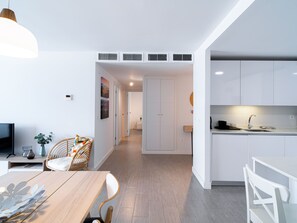 Un intérieur moderne comprenant un coin repas, une cuisine et un couloir menant à une chambre.