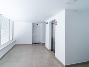 A corridor with a door marked 'C', a no-smoking sign, and a lift. - Duna Beach Torrox Costa by Casasol by Interhome (Torrox Costa)