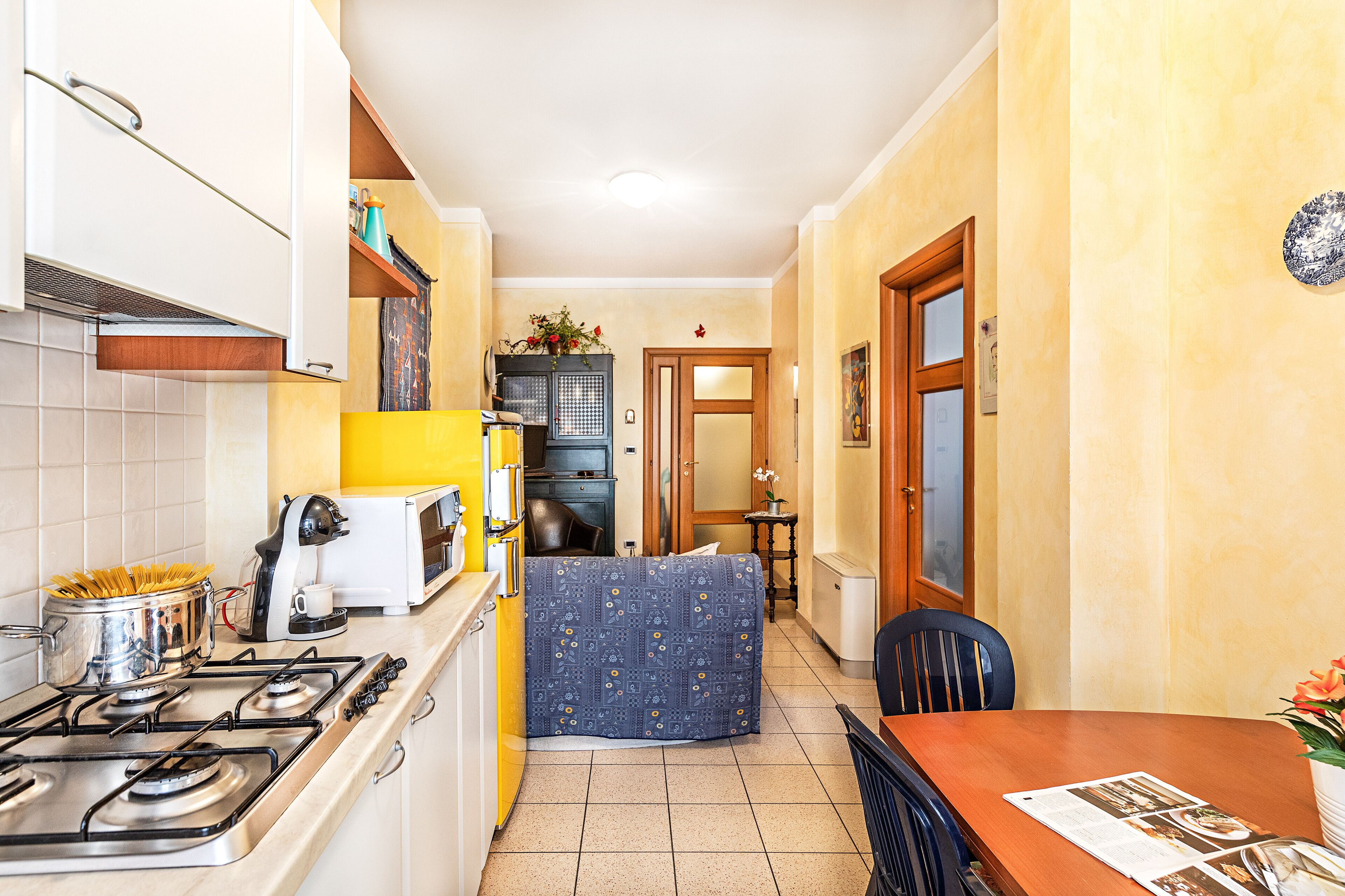 Una cocina compacta con estufa, cafetera y un pequeño comedor con mesa y sillas.