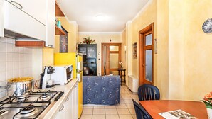 Una cocina compacta con estufa, cafetera y un pequeño comedor con mesa y sillas.