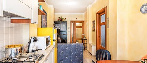A compact kitchen with a stove, a coffee machine, and a small dining area with a table and chairs.