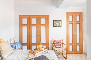 A room with a bed, a bedside table with a lamp, a chair, and a tray with breakfast items. - Gaudio Flat near Ariston Theater by Wonderful Italy (Sanremo)