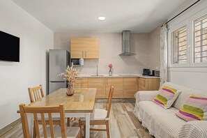 Eine kleine Küche mit Holzausstattung, einer eingebauten Mikrowelle und einem Edelstahlkühlschrank.