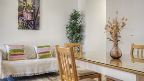 A modern living room with a glass-top dining table, wooden chairs, a striped sofa, and a potted plant. - Holiday Home 'El Islote del Sur' with Private Pool, Wi-Fi & Air Conditioning (Conil de la Frontera)