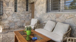 A stone-walled room with a sofa and chairs, a window with bars, and a glass coffee table with a flower vase. - Holiday Home 'El Islote del Sur' with Private Pool, Wi-Fi & Air Conditioning (Conil de la Frontera)