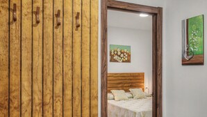 A bedroom with a wooden wardrobe, a bed with floral bedding, and a painting of flowers on the wall. - Holiday Home 'El Islote del Sur' with Private Pool, Wi-Fi & Air Conditioning (Conil de la Frontera)