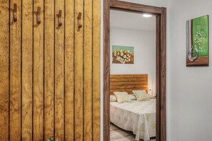 Ein Schlafzimmer mit einem Holzschrank, einem Bett mit floralem Bettzeug und einem Blumenbild an der Wand.