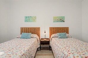 A room with two beds, each with a wooden headboard, a nightstand with a lamp, and two wall-mounted paintings. - Holiday Home 'El Islote del Sur' with Private Pool, Wi-Fi & Air Conditioning (Conil de la Frontera)