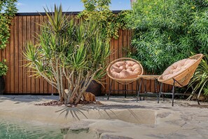 A garden with a small pool, two wicker chairs, and a wooden fence. - Holiday Home 'El Islote del Sur' with Private Pool, Wi-Fi & Air Conditioning (Conil de la Frontera)